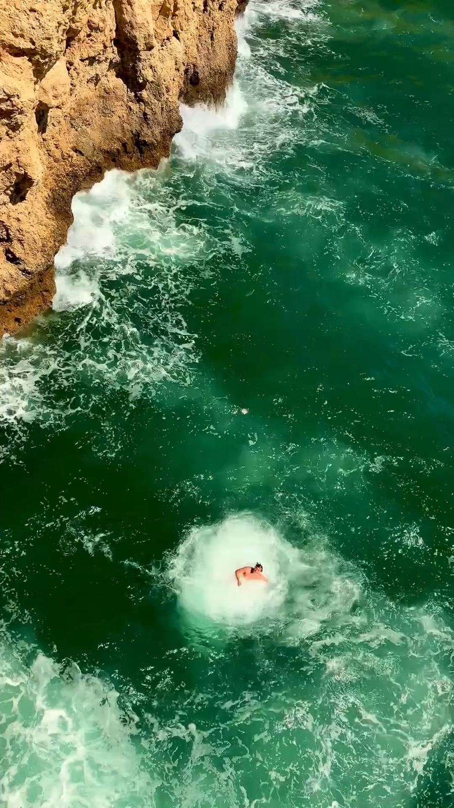 A cliff jump landing in bright green ocean water