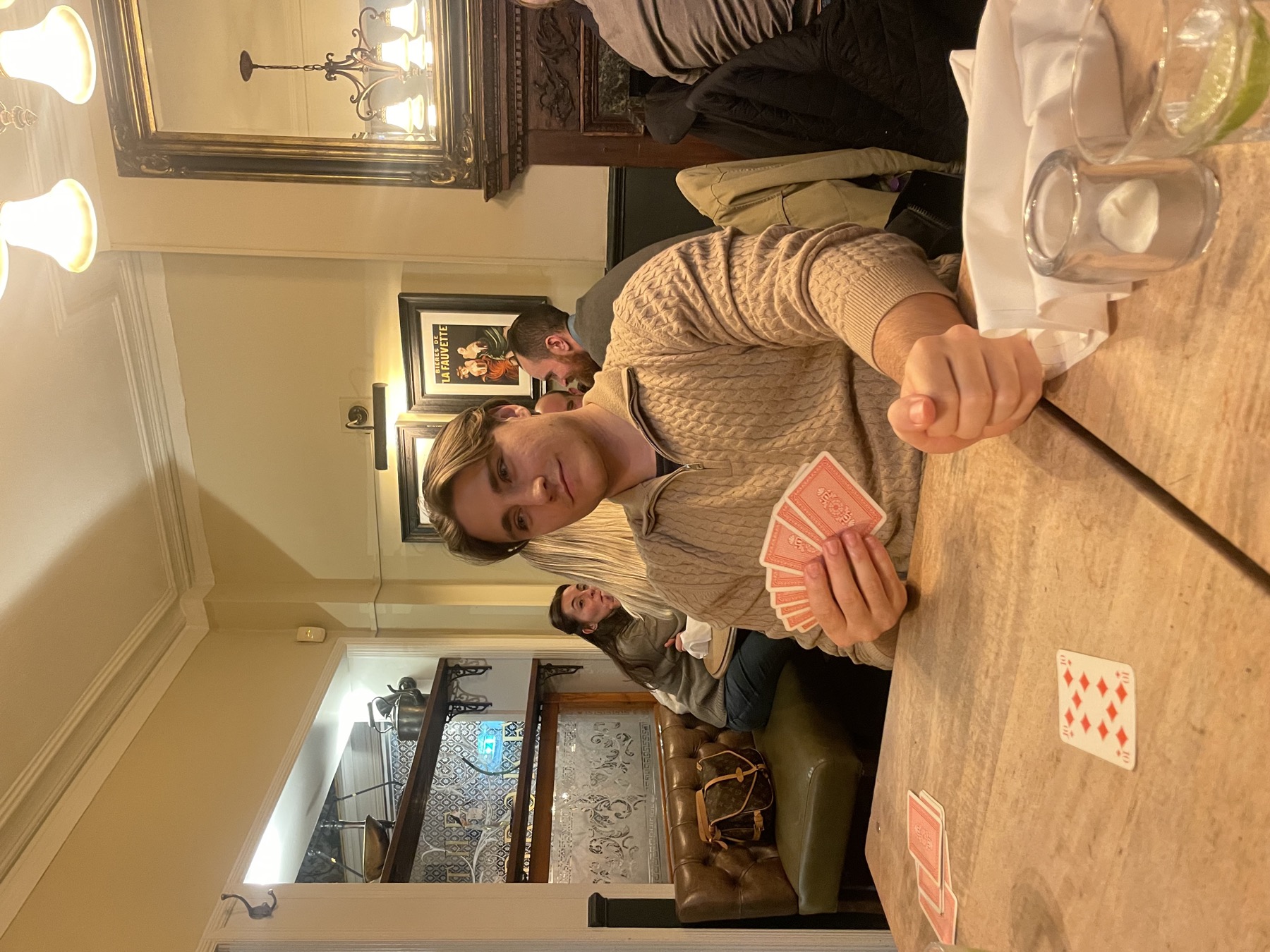 Angelo holding a hand of cards at a pub table