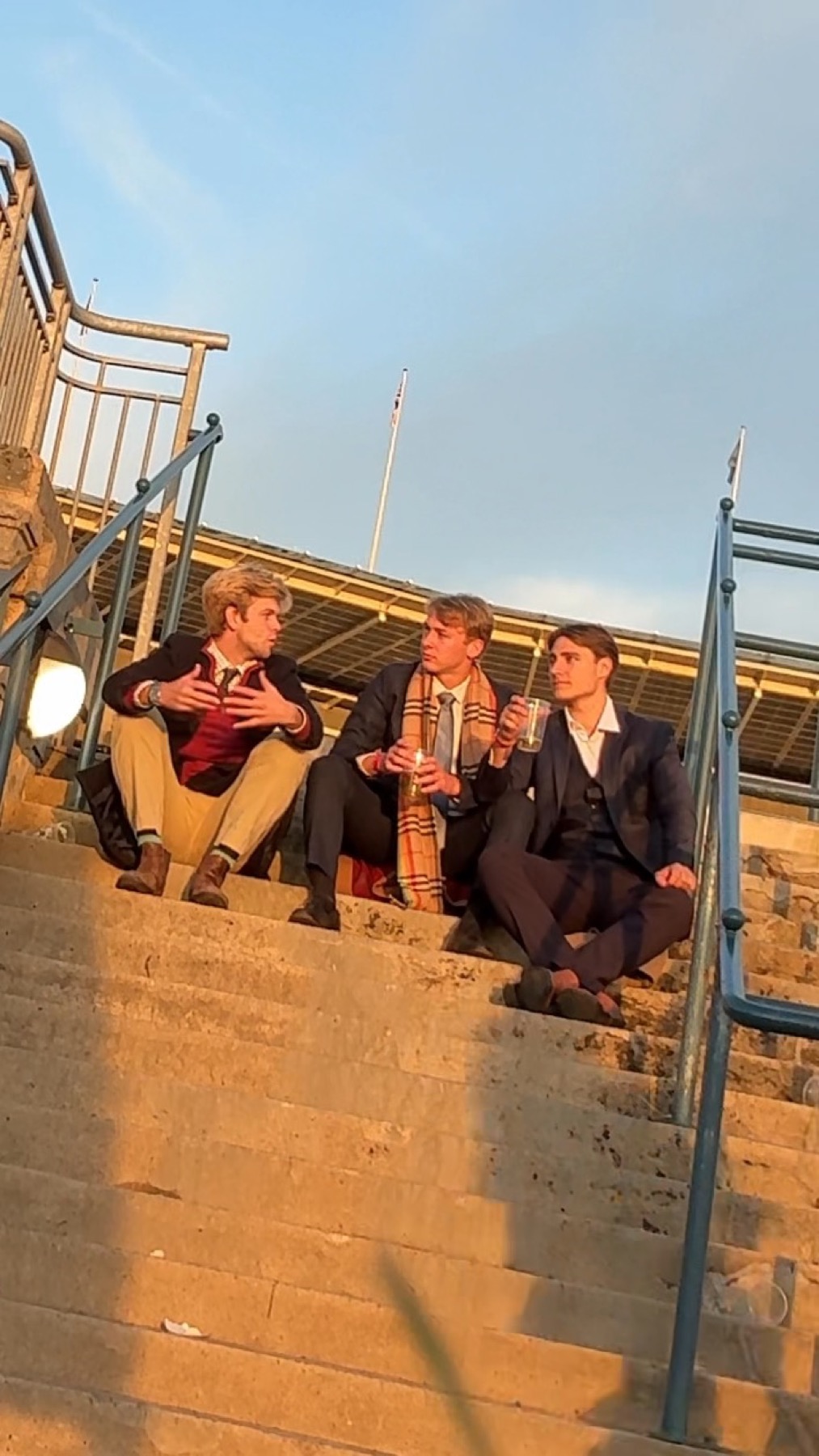 Angelo and friends sitting on steps at sunset in formalwear