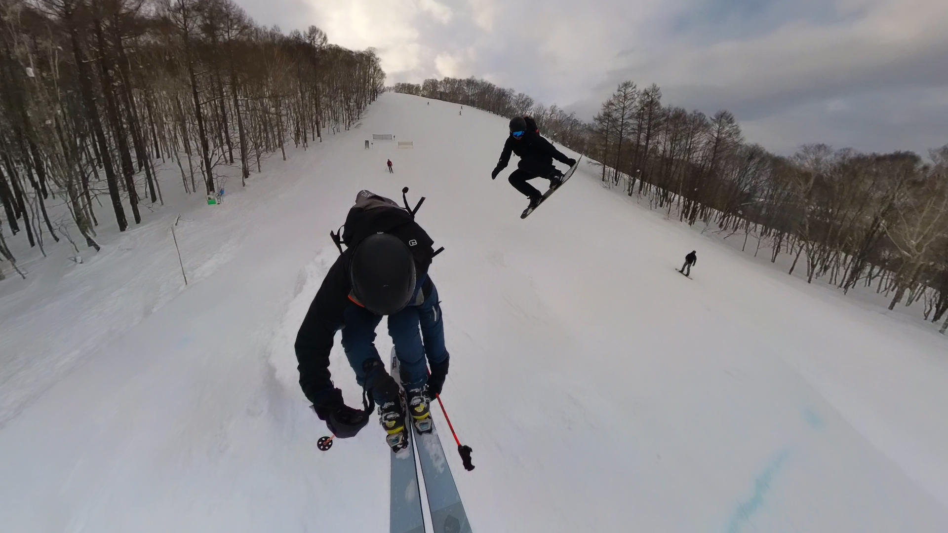 A ski jump scene with Angelo and a friend against a bright alpine sky
